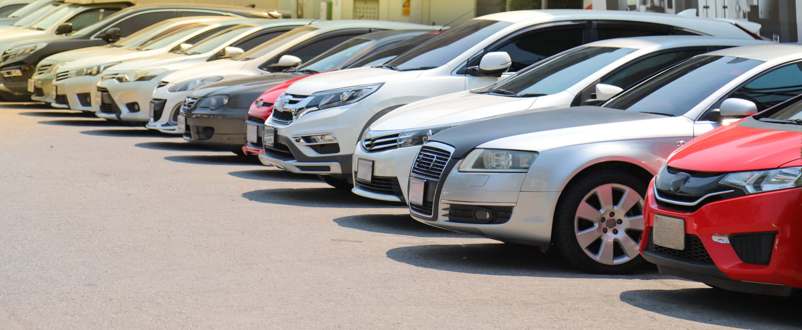 Closeup of front side of  cars parking in outdoor parking lot beside the street beside the street in bright sunny day.